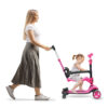full length profile shot of a mother pushing a girl on a tricycl
